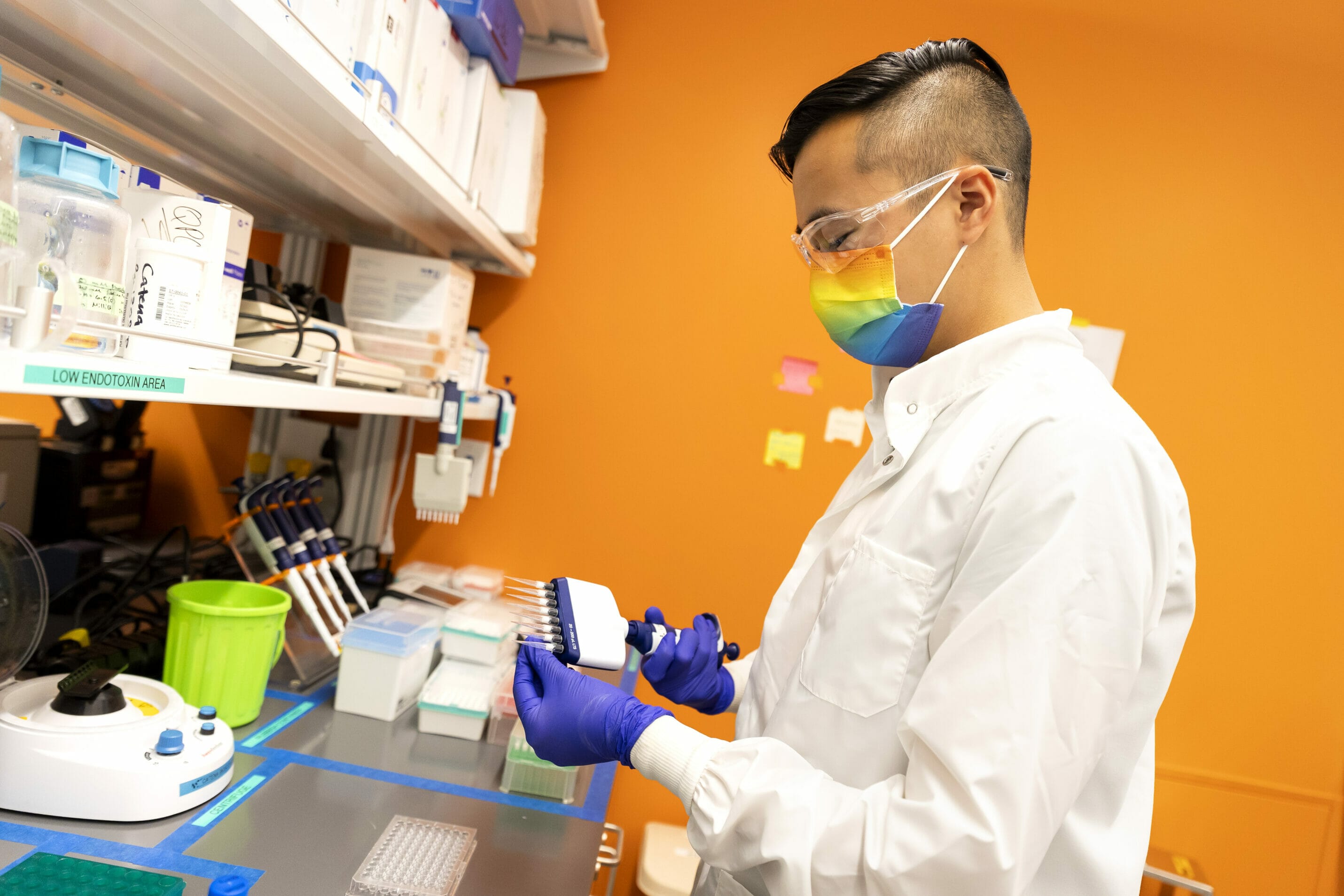 Catena scientist Max Nguyen, wearing rainbow mask, working in the lab