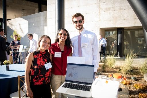 Three people (from Axent Biosciences) at a table in the Bakar Labs courtyard